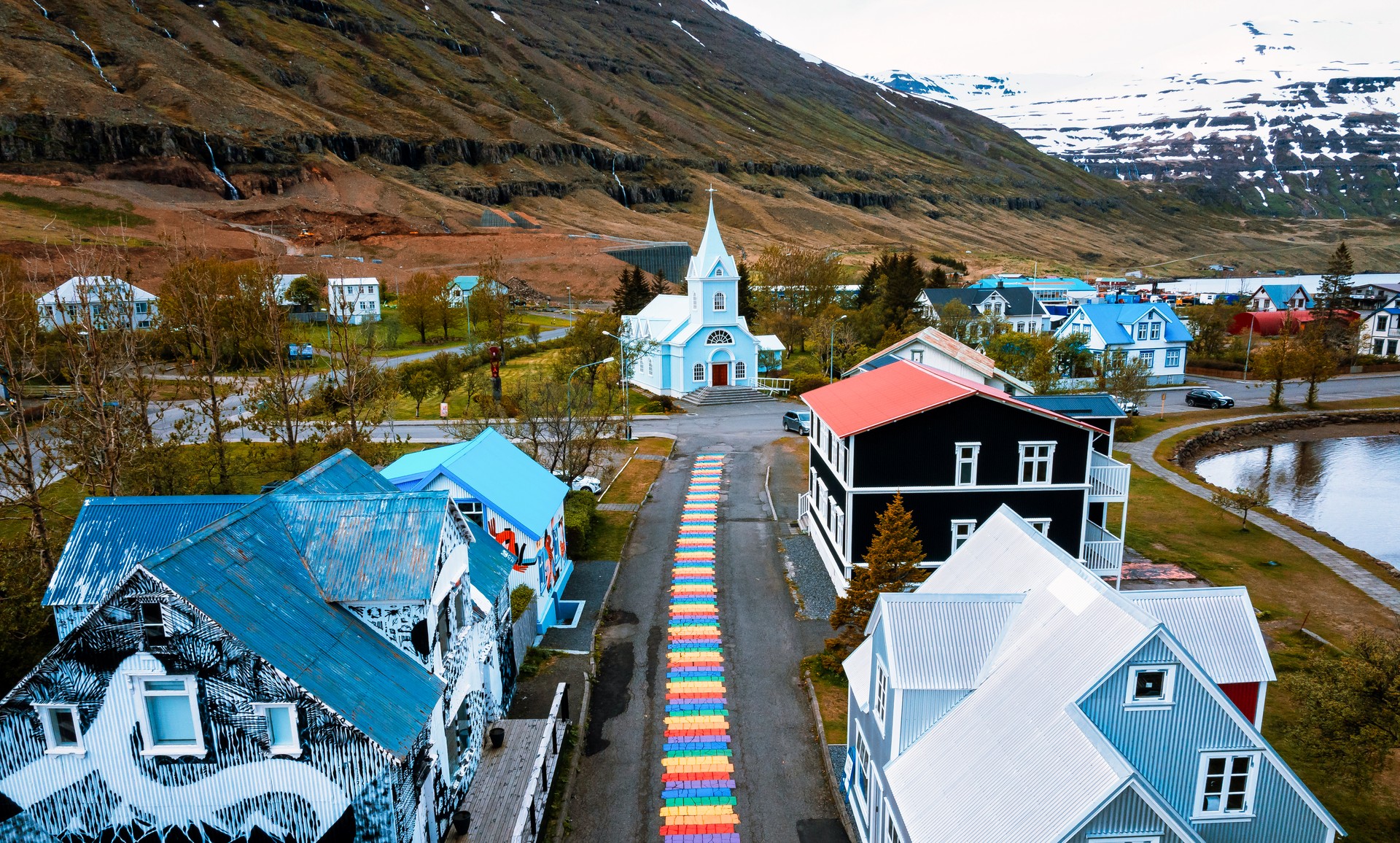 Aerial view of the Seydisfjordur town in Iceland. The famous rainbow road in Seydisfjordur with icelandic buildings around show artwork painted walls.